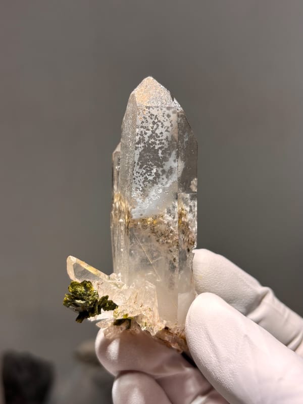 Clear quartz point with green epidote inclusion from Sichuan, China, close-up of the crystal faces