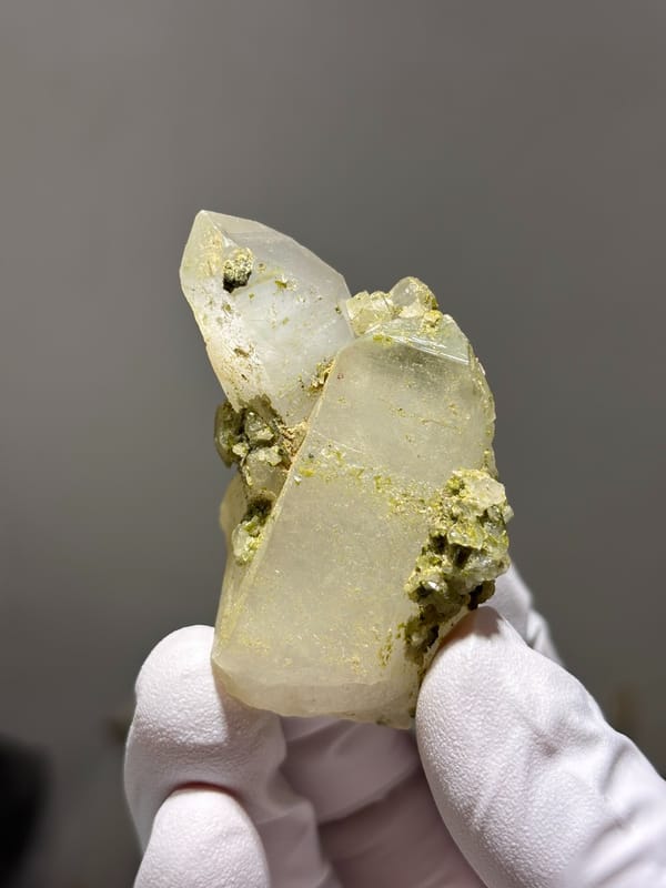 Milky quartz point with green epidote on floater base from Sichuan, China, close-up of the crystal faces