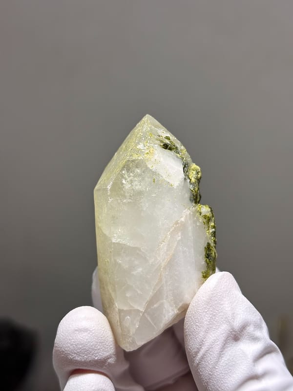 Milky quartz point with green epidote on its face from Sichuan, China, close-up of the crystal faces