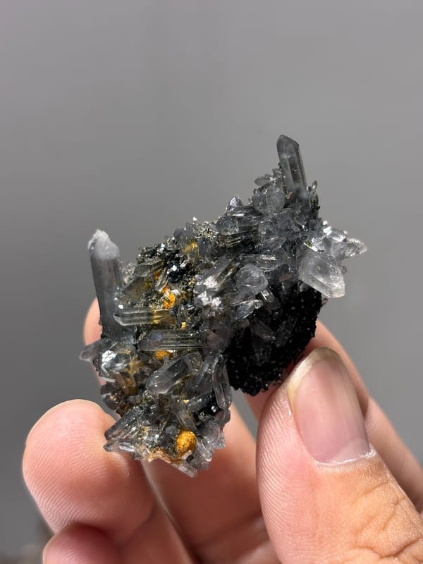 Grey quartz cluster with epidote and orange flecks from Yunnan, China, close-up of the crystal faces