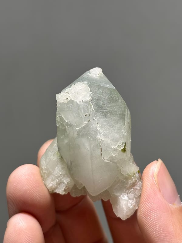 Pale green epidote quartz floater with complete tip from Sichuan, China, close-up of the crystal faces