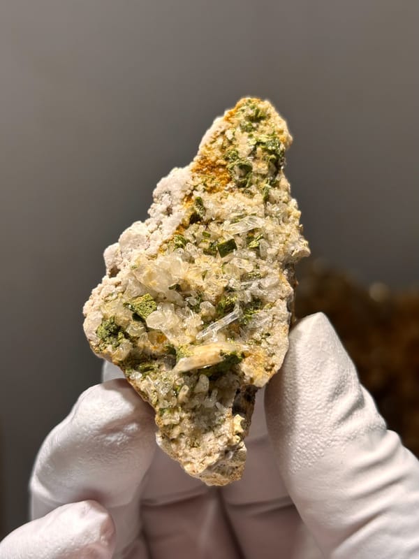Green epidote in quartz-feldspar slab from Meigu, Sichuan, China, close-up of the crystal faces