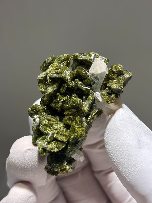 Olive-green epidote cluster with white-capped quartz from Sichuan, China, held in gloved hand