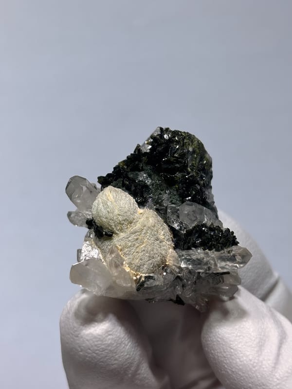 Pale green prehnite ball with quartz and dark epidote from Yunnan, China, close-up of the crystal faces