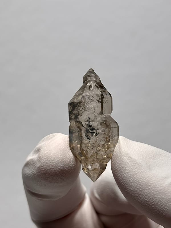 Smoky double-terminated quartz with sceptre tip from Yunnan, China, held in gloved hand