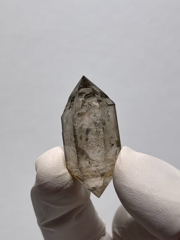 Smoky double-terminated quartz with phantom from Yunnan, China, held in gloved hand