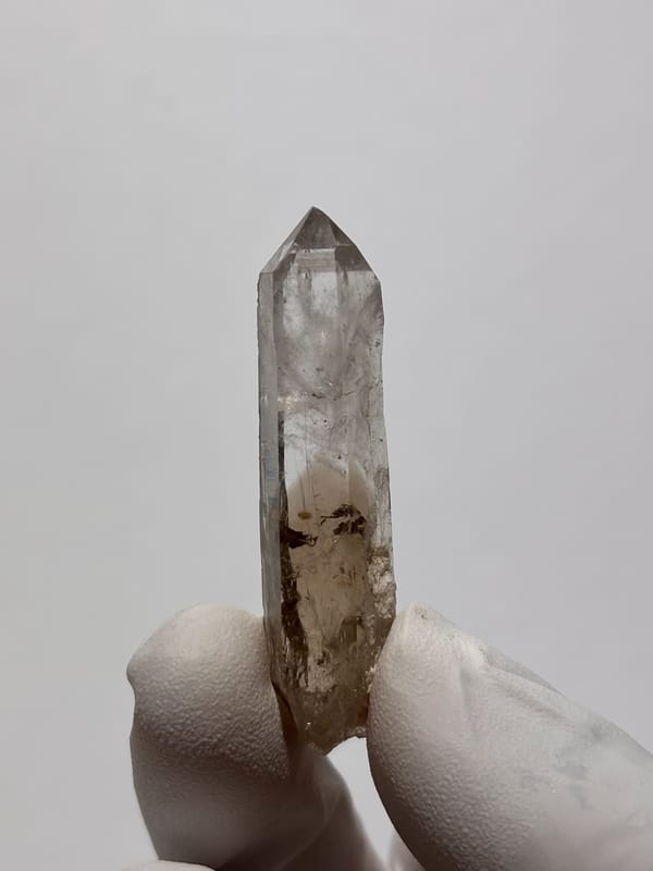 Gradient smoky quartz point from Fujian, China, held in gloved hand