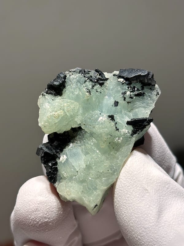 Pale green prehnite with black babingtonite from Yunnan, China, close-up of the crystal faces