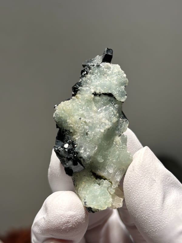 Black babingtonite crystals on pale green prehnite from Yunnan, China, close-up of the crystal faces