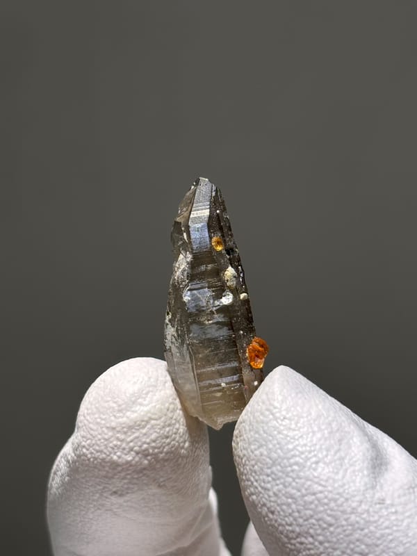 Tiny smoky quartz with Fanta-orange spessartine from Fujian, China, close-up of the crystal faces
