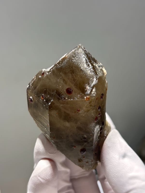 Smoky quartz point with red garnets from Fujian, China, close-up of the crystal faces