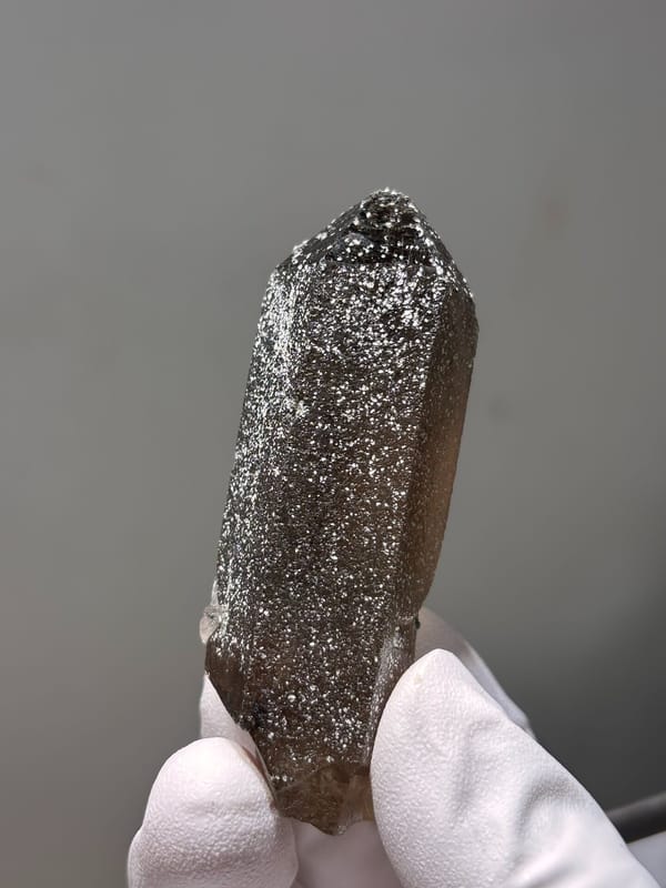 Dark smoky quartz point with mica-dusted tip from Fujian, China, top view