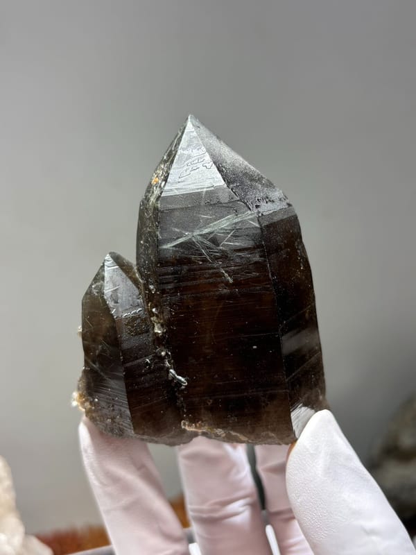 Smoky quartz floater from Brazil, held in gloved hand