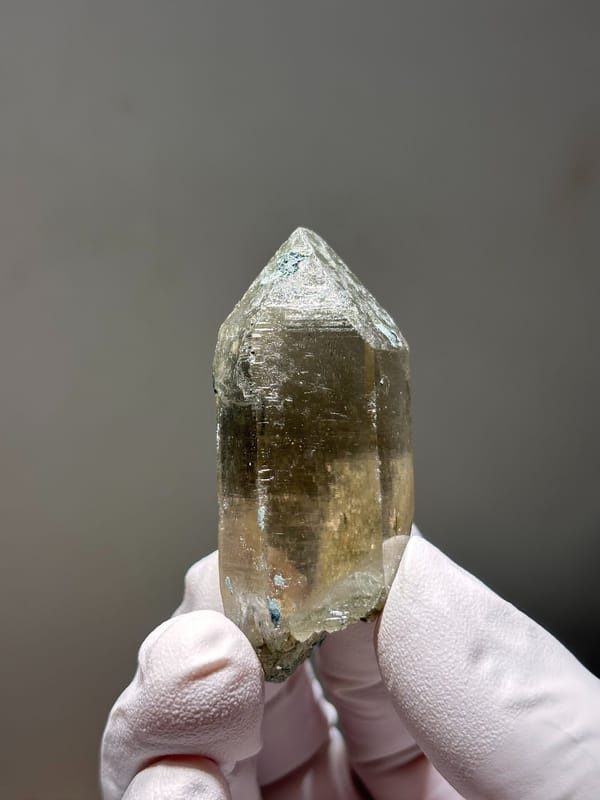 Smoky quartz floater with complete tip from Fujian, China, held in gloved hand