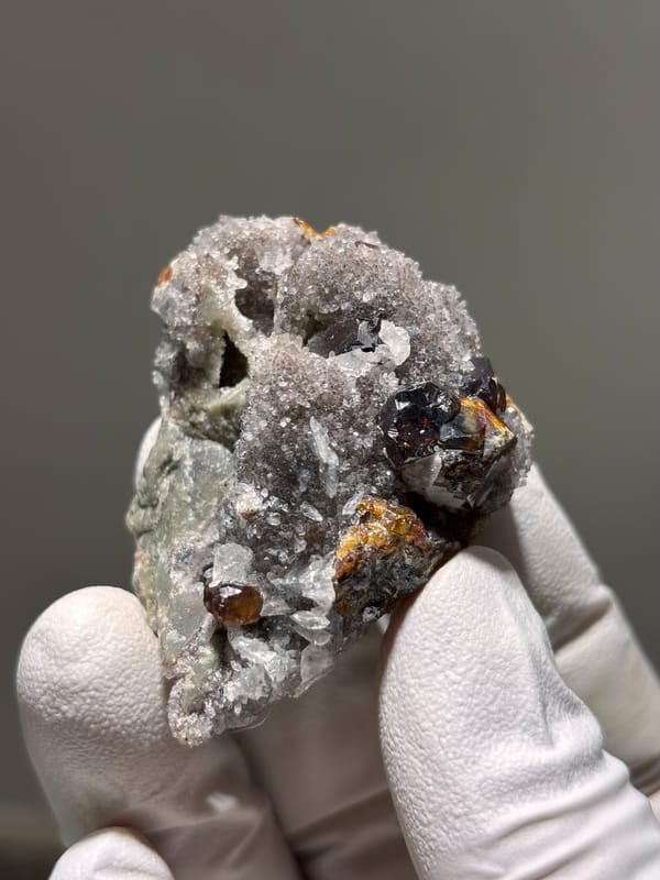 Dark red-brown sphalerite crystals on grey quartz from Hubei, China, close-up of the crystal faces