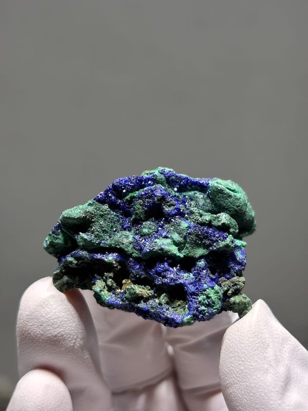Deep blue azurite crust with green malachite from Hubei, China, held in gloved hand