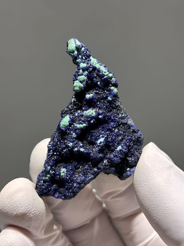 Deep blue azurite plate with green malachite spots from Hubei, China, held in gloved hand