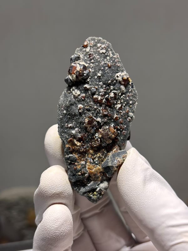 Red-brown sphalerite crystals on grey plate from Hebei, China, close-up of the crystal faces