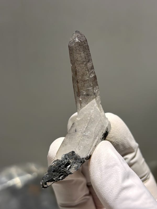 Smoky quartz point on specular hematite base from Guangdong, China, close-up of the crystal faces