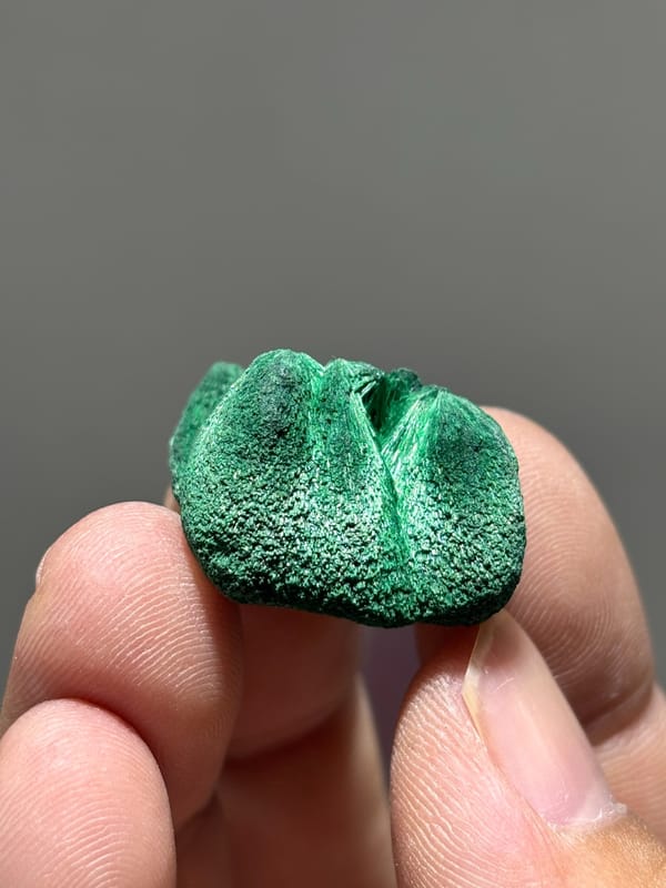 Tiny velvet malachite nodule with silky sheen from Guangdong, China, held in hand