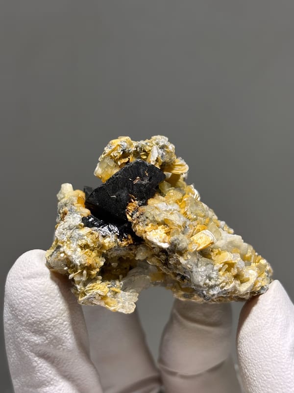 Black cassiterite crystal with aquamarine and mica from Xuebaoding, Sichuan, China, close-up of the crystal faces