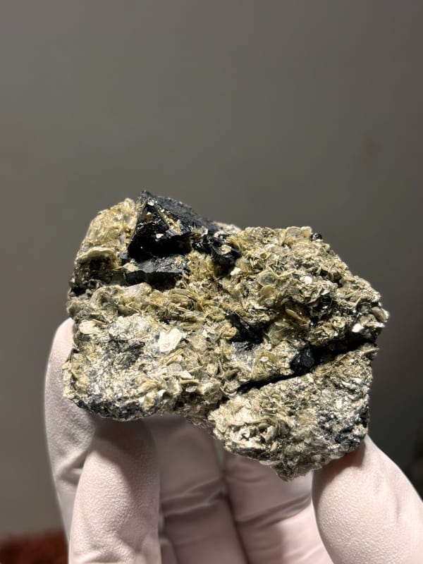 Black cassiterite crystals with aquamarine on mica from Xuebaoding, Sichuan, China, close-up of the crystal faces