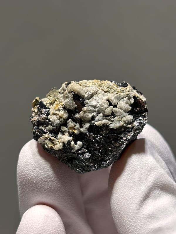 Black cassiterite with white calcite like a snow mountain from Xuebaoding, Sichuan, China, close-up of the crystal faces