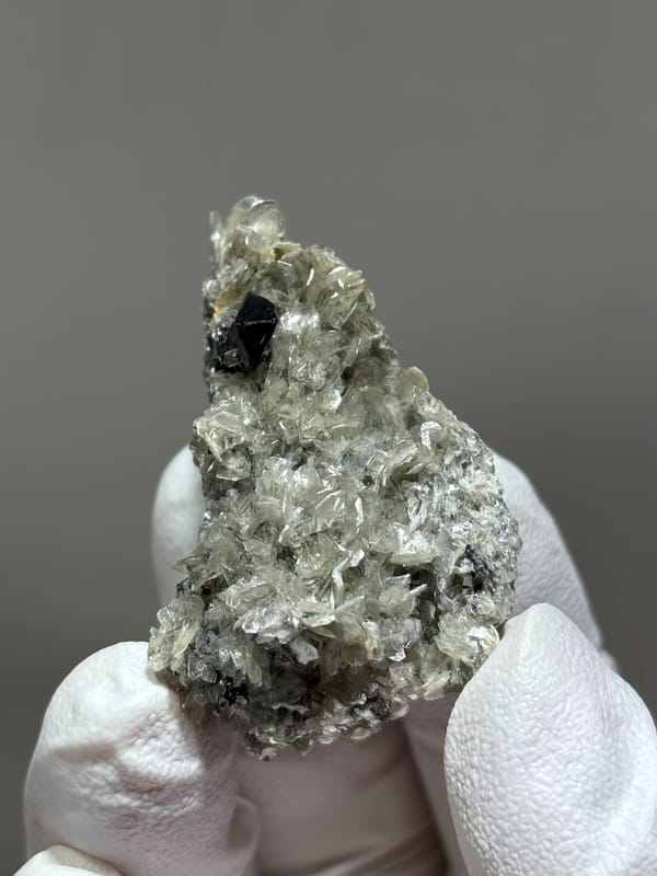 Black cassiterite crystal in pale mica from Xuebaoding, Sichuan, China, close-up of the crystal faces