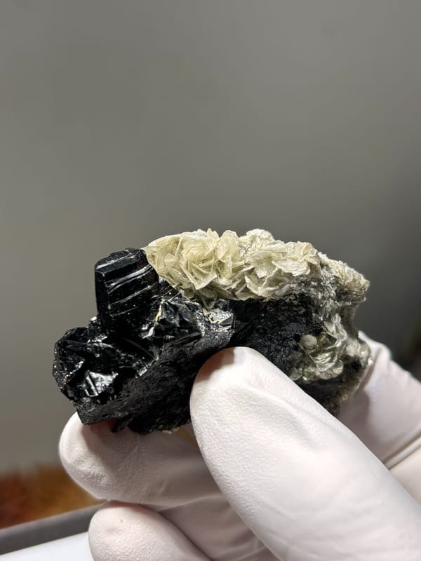 Black cassiterite plate with pale mica from Xuebaoding, Sichuan, China, close-up of the crystal faces