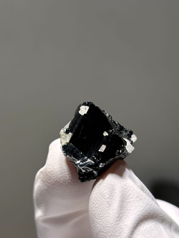 Tiny black cassiterite crystal with white flecks from Xuebaoding, Sichuan, China, second angle