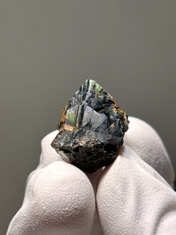 Tiny black cassiterite with iridescent sheen from Xuebaoding, Sichuan, China, close-up of the crystal faces
