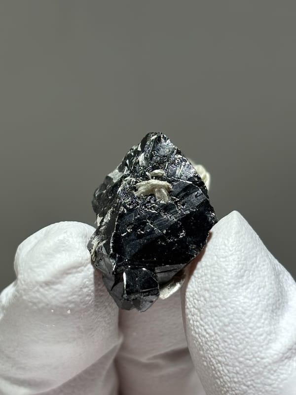 Glossy black cassiterite crystal with mica from Xuebaoding, Sichuan, China, close-up of the crystal faces