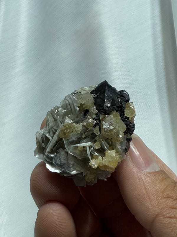 Black cassiterite with scheelite and mica from Xuebaoding, Sichuan, China, close-up of the crystal faces
