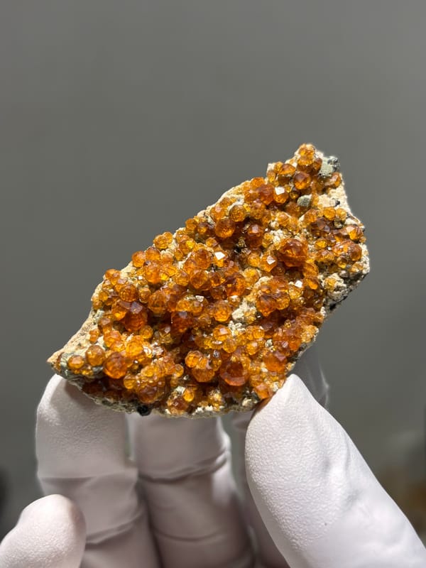 Plate of Fanta-orange spessartine on feldspar from Fujian, China, close-up of the crystal faces
