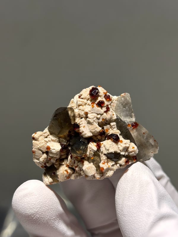 Red garnets on feldspar with smoky quartz from Fujian, China, close-up of the crystal faces