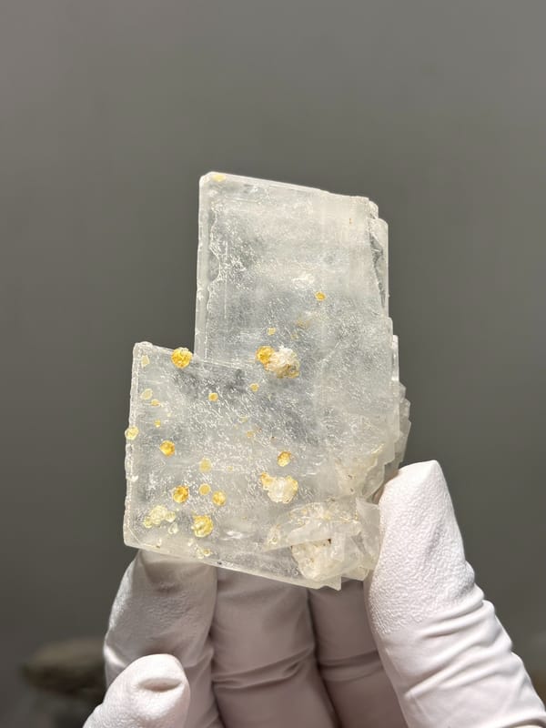 Clear baryte blade with yellow calcite specks from Sichuan, China, close-up of the crystal faces