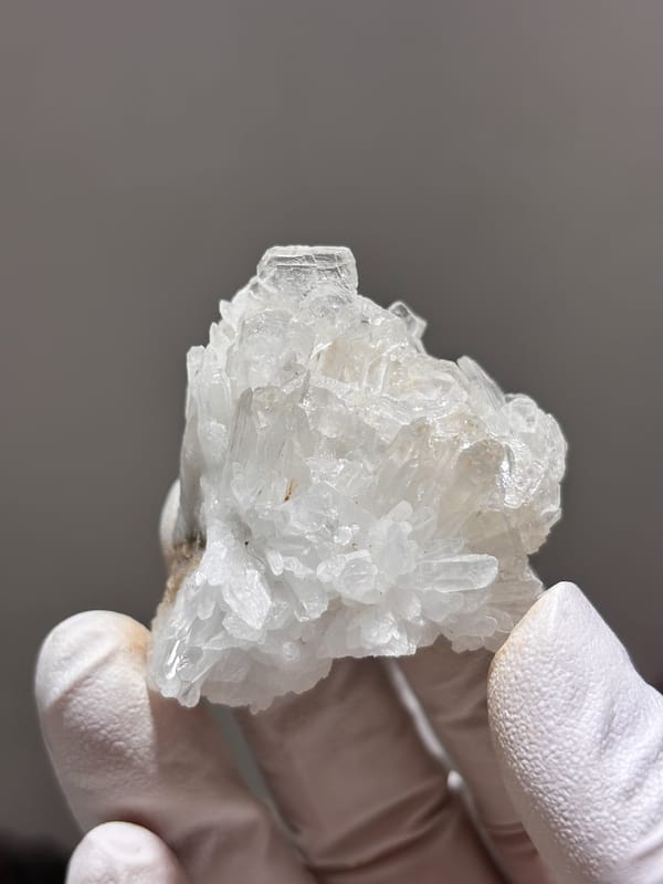 Cluster of clear baryte blades with quartz from Sichuan, China, held in gloved hand
