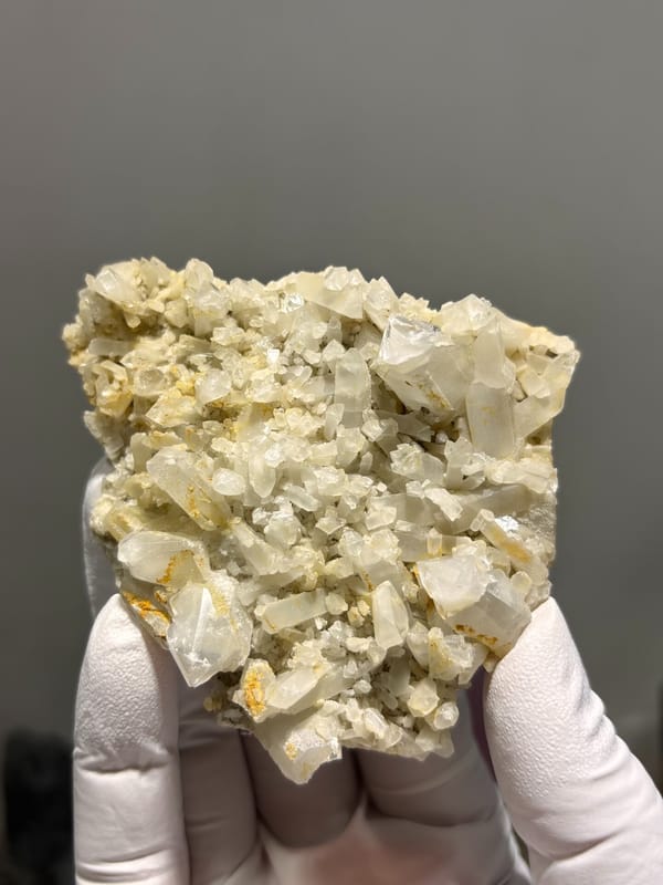 Plate of cream baryte crystals with golden staining from Sichuan, China, close-up of the crystal faces
