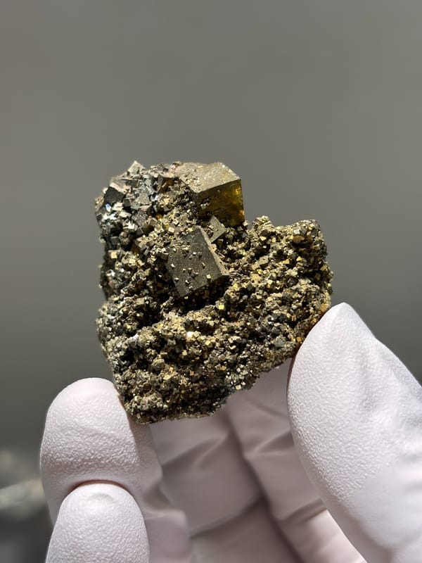 Brassy pyrite cubes on granular pyrite base from Hunan, China, close-up of the crystal faces