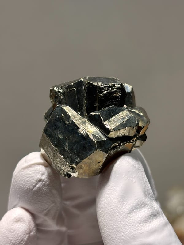 Brassy pyrite crystal ball from Indonesia, held in gloved hand