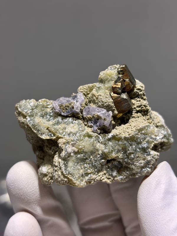 Brassy pyrite crystal with purple fluorite on grey matrix from Inner Mongolia, China, second angle