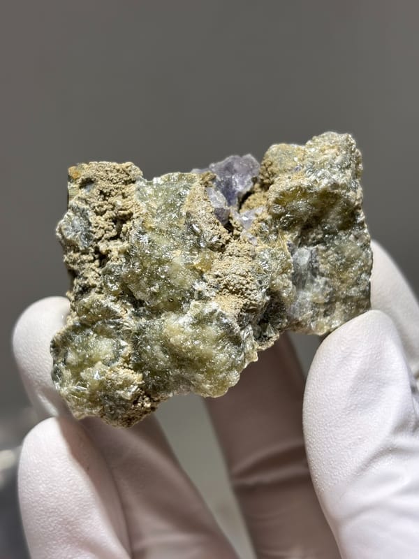 Brassy pyrite crystal with purple fluorite on grey matrix from Inner Mongolia, China, close-up of the crystal faces