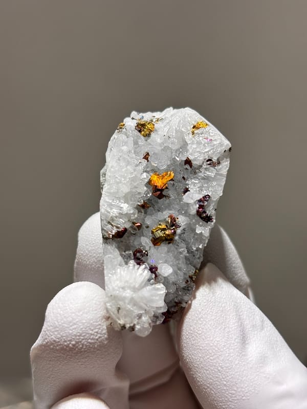 White quartz with iridescent pyrite from Hubei, China, held in gloved hand