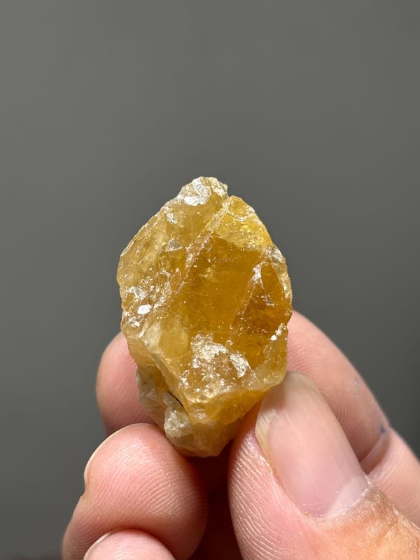 Golden-orange scheelite crystal from Xuebaoding, Sichuan, China, held in hand