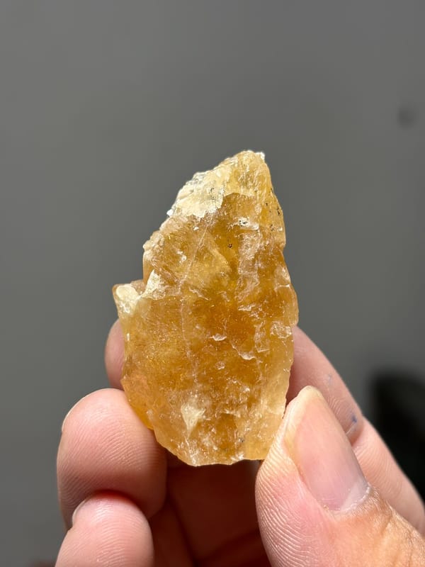 Golden-yellow scheelite crystal from Xuebaoding, Sichuan, China, held in hand