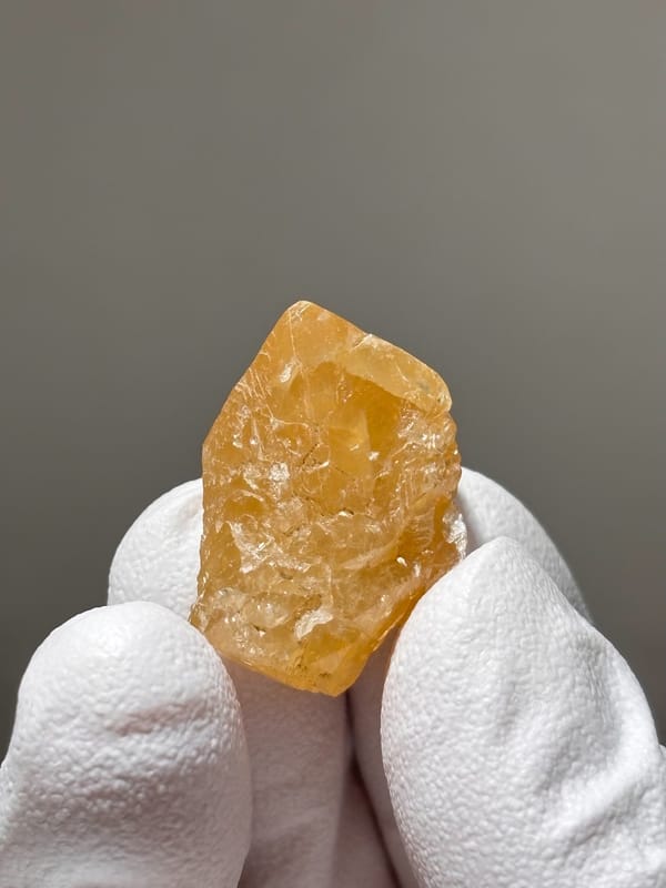 Small honey scheelite with white calcite spots from Xuebaoding, Sichuan, China, close-up of the crystal faces