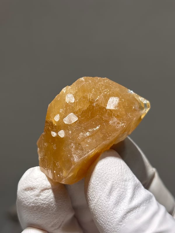 Honey scheelite with white calcite specks from Xuebaoding, Sichuan, China, close-up of the crystal faces
