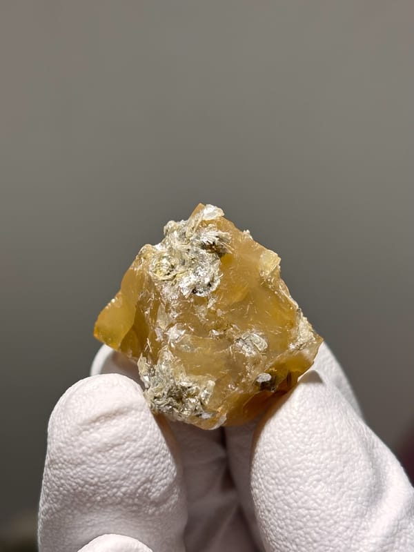 Honey scheelite with white mica flakes from Xuebaoding, Sichuan, China, close-up of the crystal faces