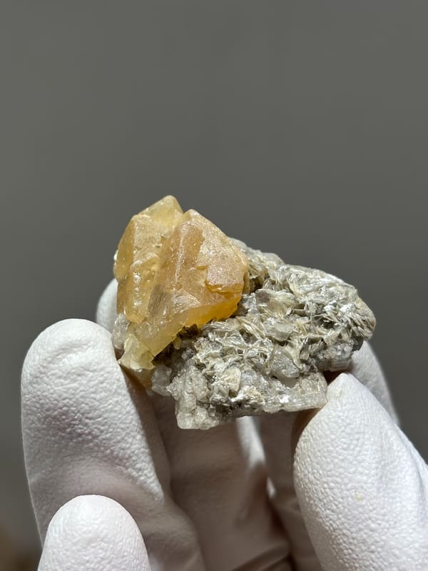 Honey scheelite crystal on mica with calcite base from Xuebaoding, Sichuan, China, second angle