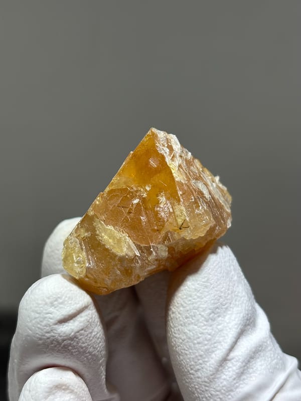 Honey scheelite with mica flakes on its faces from Xuebaoding, Sichuan, China, close-up of the crystal faces